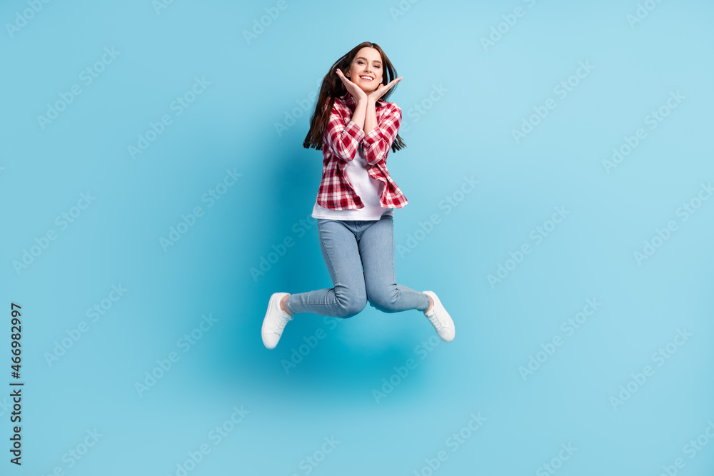 Full size photo of happy cheerful nice woman jump up smile hands face isolated on pastel blue color background Full size photo of happy cheerful nice woman jump up smile hands face isolated on pastel blue color background