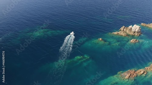 Aerial tracking shot of a motorboat in motion, on an amazing blue sea near the rocky rough coast. photo