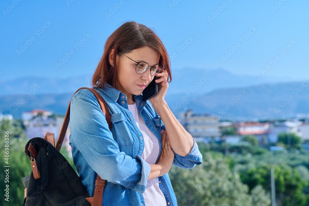 Confident serious middle aged woman talking on the phone outdoors
