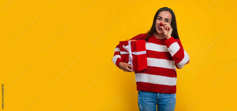 Banner photo of happy excited young brunette woman with gift box in hands isolated on yellow background Banner photo of happy excited young brunette woman with gift box in hands isolated on yellow background