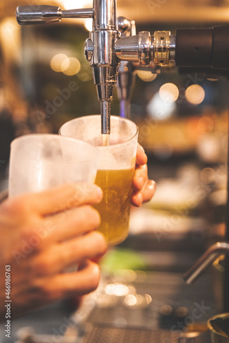 Waiter serving beer in a glass with a beer shooter.