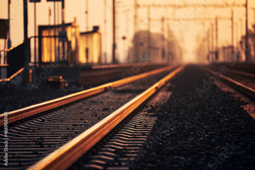 Railway at golden sunrise. Selective focus railroad track in train station.