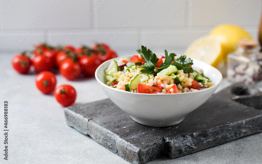 Eastern bulgur and vegetable tabbouleh salad in a plate. Vegetarian dish.