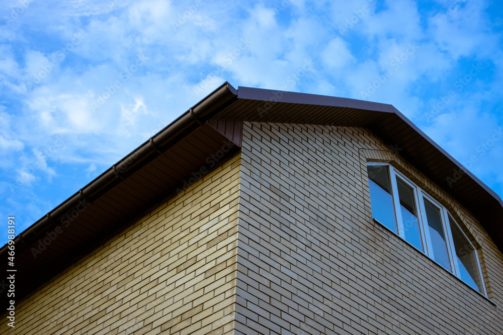 Corner of a tall brick house with a window in the attic Corner of a tall brick house with a window in the attic