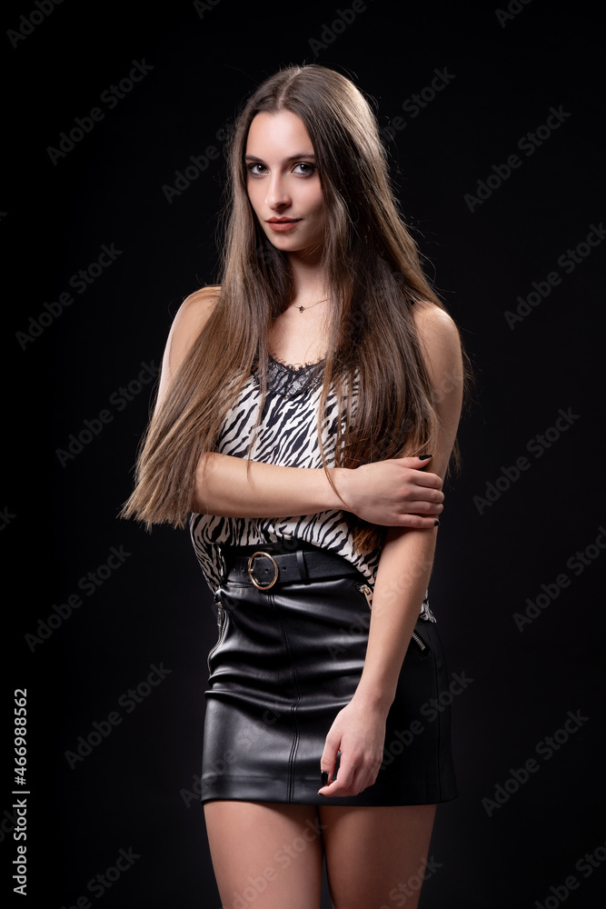 Beautiful woman on black background in leather skirt and patterned shirt Beautiful woman on black background in leather skirt and patterned shirt