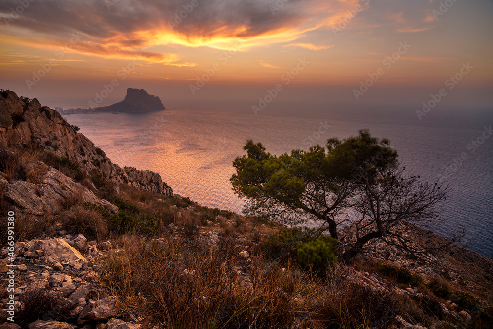 Coastal landscape at sunrise with sea view and mountain on the horizon. With the peon of Ifach on the horizon.