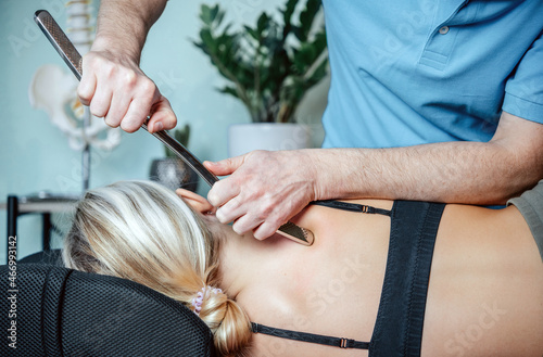 Chiropractor performing myofascial release techniques with IASTM tool for the Rhomboids