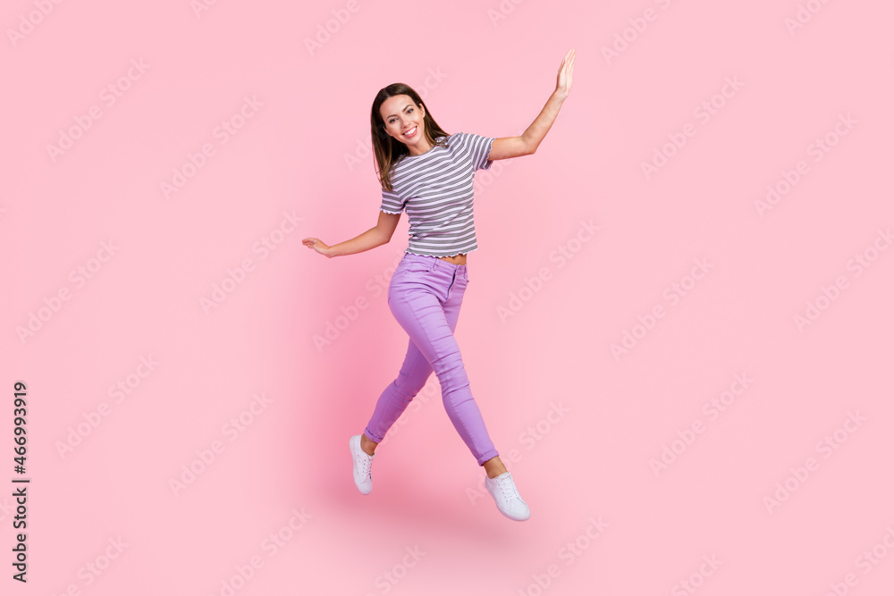 Photo of pretty adorable young lady wear striped outfit smiling jumping high walking isolated pink color background Photo of pretty adorable young lady wear striped outfit smiling jumping high walking isolated pink color background