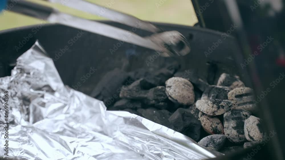 Burning charcoal inside the barbecue smoker, man in gloves using
