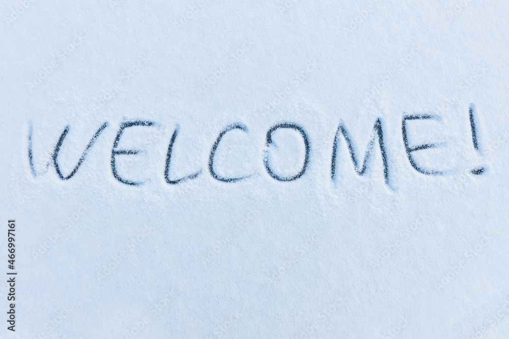 Handwritten word welcome on a snowy surface. Winter holidays concept background.