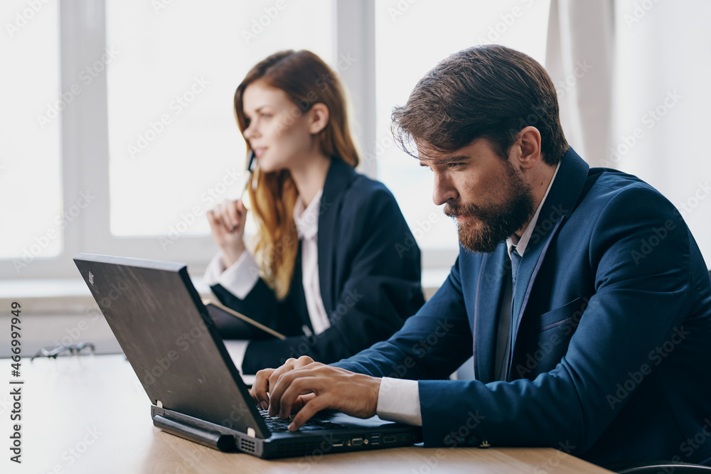 colleagues sitting at a desk with a laptop communication finance officials colleagues sitting at a desk with a laptop communication finance officials