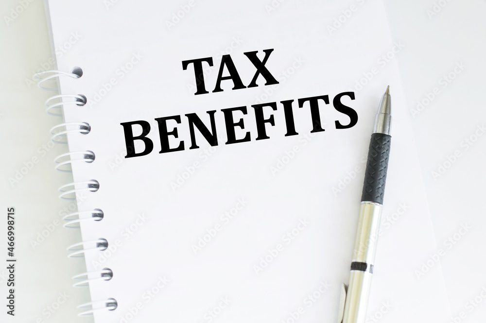 On a white notepad the inscription TAX BENEFITS on a white background next to the pen. On a white notepad the inscription TAX BENEFITS on a white background next to the pen.