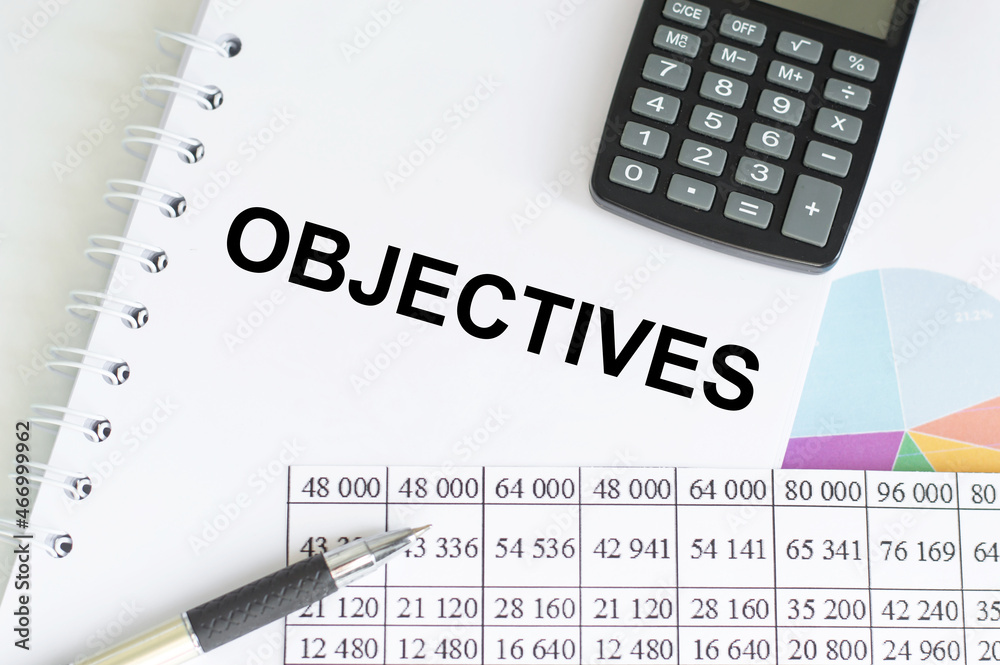 Paper with text objective on the table next to a calculator, a pen and financial reports Paper with text objective on the table next to a calculator, a pen and financial reports