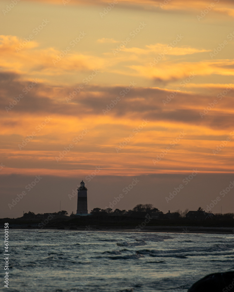 sunset over the sea with a lighthouse