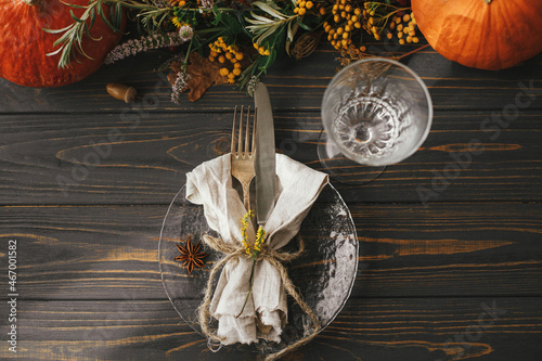 Modern plate with vintage cutlery, linen napkin, herb and glass on wooden table with pumpkins and autumn flowers arrangement. Rustic farmhouse wedding. Thanksgiving dinner table setting