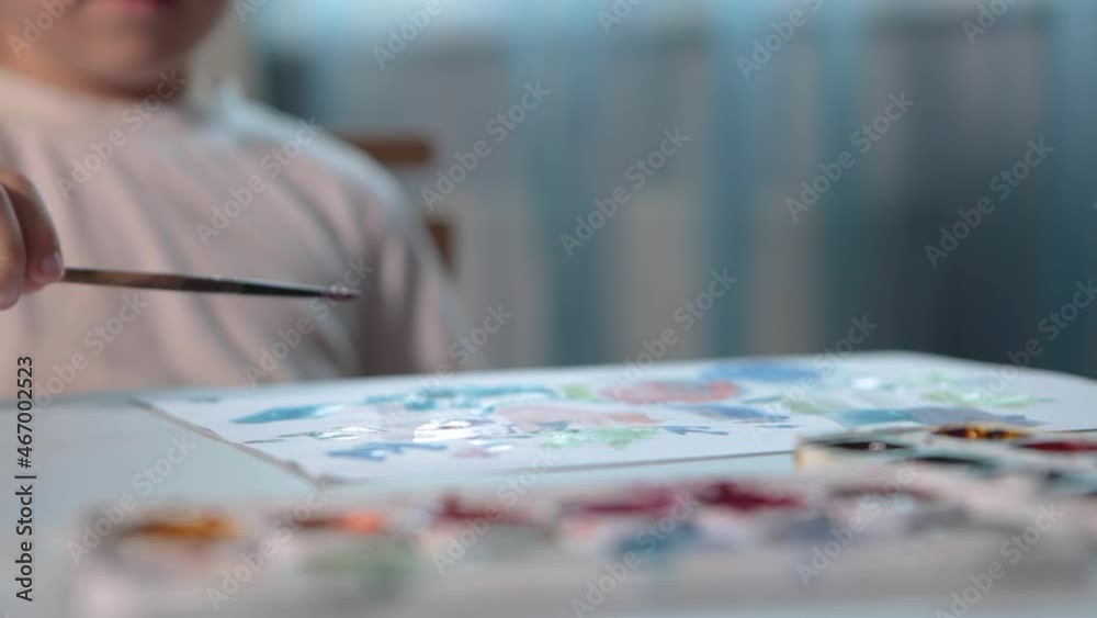 A boy draws with paints at a table in his room. High quality FullHD footageA boy draws with paints at a table in his room.