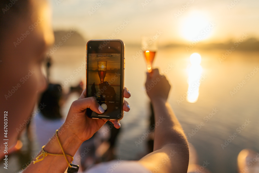 Fototapeta premium glass of champaigne, shot on mobile phone, morning sunrise on the river