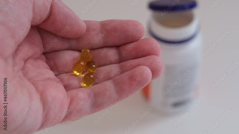 A man holding vitamin D3 capsules in his hand. Close up. A man holding vitamin D3 capsules in his hand. Close up.