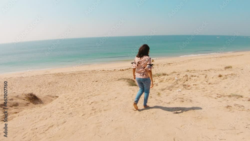 Young woman walking alone at tropical blue beach during bright sunny day of winter. Vacation holiday concept Young woman walking alone at tropical blue beach during bright sunny day of winter. Vacation holiday concept