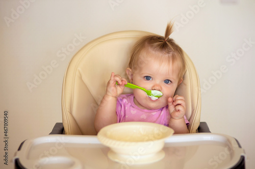 happy baby sitting at the table in the kitchen and eating with an appetite
