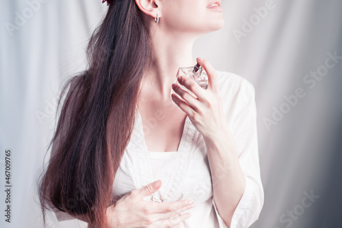 girl sprays herself perfume on her neck