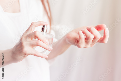 girl sprays herself perfume on her wrist
