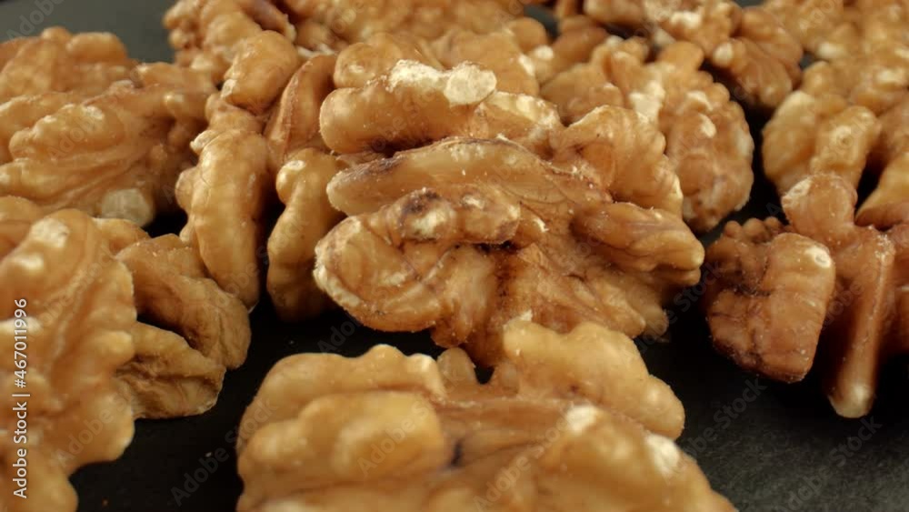 A heap of light brown walnuts on the dark surface of the table. Fruits of the walnut tree. The concept of healthy food. Vegetarian food. High quality. 4k footage. A heap of light brown walnuts on the dark surface of the table. Fruits of the walnut tree. The concept of healthy food. Vegetarian food. High quality. 4k footage.