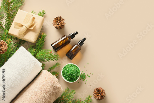 Christmas Spa concept with cosmetic aroma oil, pine cones, evergreen branches on beige background. Winter holiday for body care and wellness. View from above. Special offer for beauty saloon.