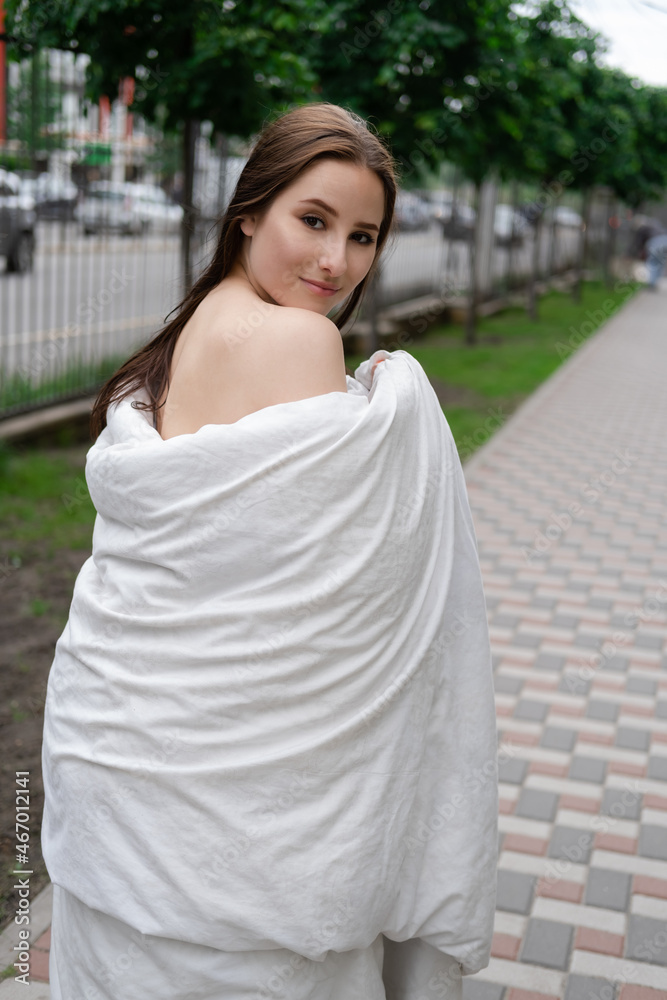 pretty girl in a white blanket walking by the street