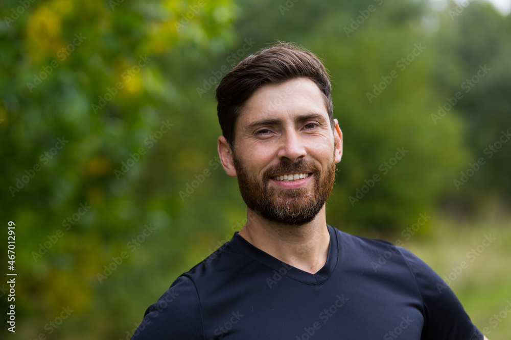 Close up portrait young happy bearded man standing in nature between forest trees relaxes, breathes fresh air closing his eyes. Male enjoys a life of peace calm, quiet in the park. Outdoors. Happiness Close up portrait young happy bearded man standing in nature between forest trees relaxes, breathes fresh air closing his eyes. Male enjoys a life of peace calm, quiet in the park. Outdoors. Happiness