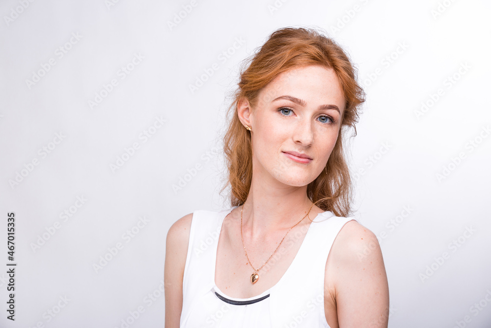 Portrait of a beautiful young woman of European, Caucasian nationality with long red hair and freckles on her face posing on a white background in the studio. Close-up student girl in a white blouse Portrait of a beautiful young woman of European, Caucasian nationality with long red hair and freckles on her face posing on a white background in the studio. Close-up student girl in a white blouse