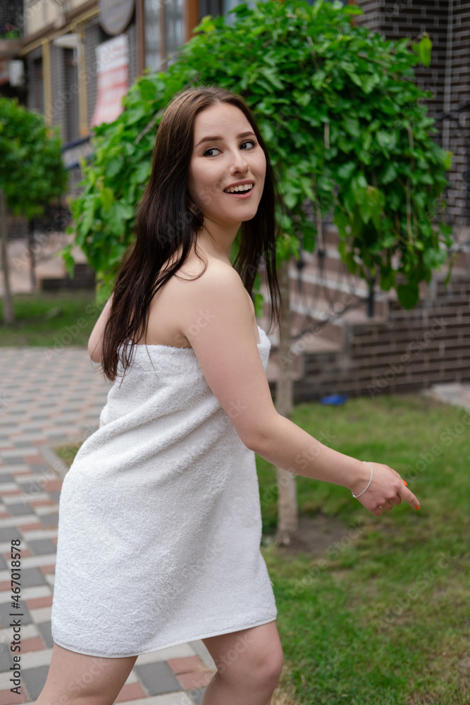 confident brunette woman in white towel running by the street. crazy beautiful millennial carefree girl.