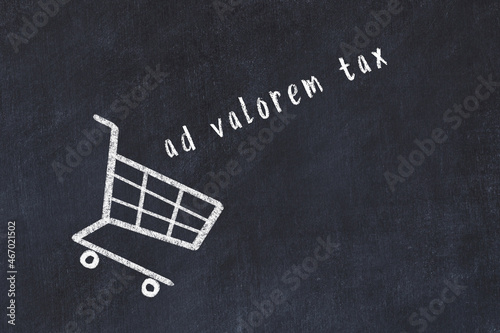 Chalk drawing of shopping cart and word ad valorem tax on black chalboard. Concept of globalization and mass consuming photo