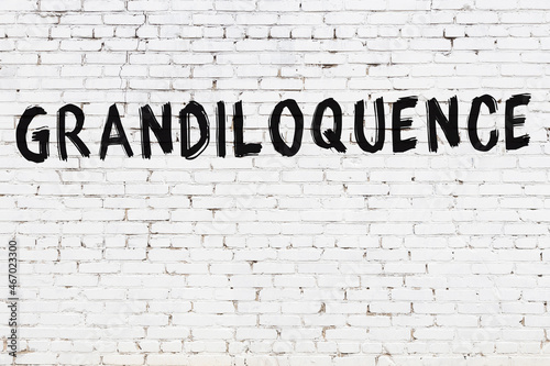 Inscription grandiloquence painted on white brick wall
