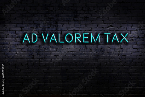 Night view of neon sign on brick wall with inscription ad valorem tax photo