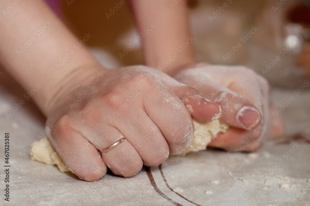 Making dough for a pie or baking bread with women's hands on a table with flour
