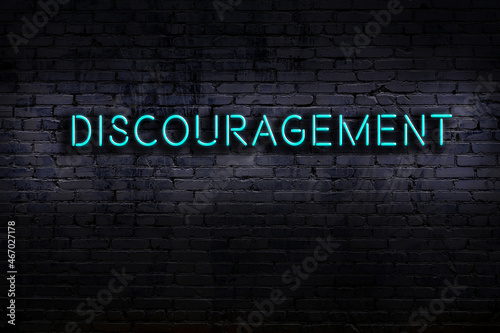 Neon sign. Word discouragement against brick wall. Night view photo