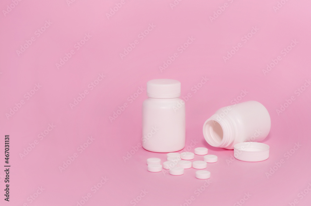 Two unmarked white medicine bottles and scattered pills on a pink background