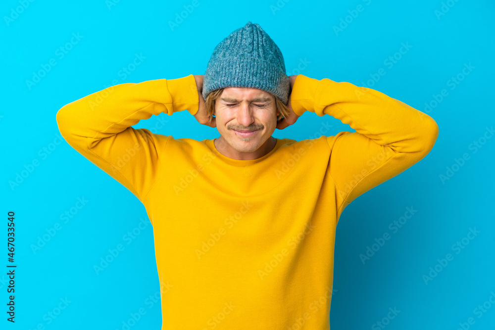 Handsome blonde man isolated on blue background frustrated and covering ears Handsome blonde man isolated on blue background frustrated and covering ears