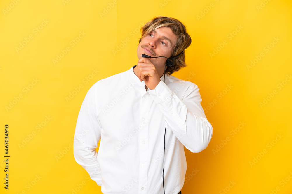 Telemarketer man working with a headset isolated on yellow background and looking up Telemarketer man working with a headset isolated on yellow background and looking up