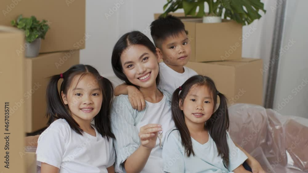 Japanese Family Holding New Home Key Among Moving Boxes Indoor Japanese Family Holding New Home Key Among Moving Boxes Indoor