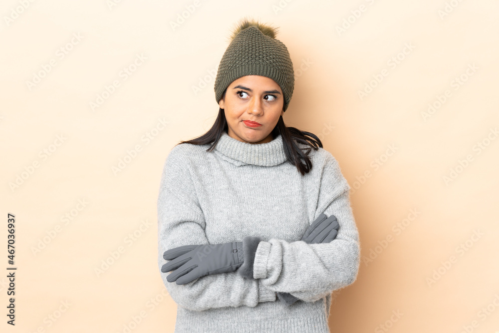 Young Colombian girl with winter hat isolated on beige background thinking an idea Young Colombian girl with winter hat isolated on beige background thinking an idea