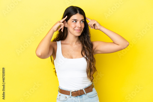 Young caucasian woman isolated on yellow background having doubts and thinking