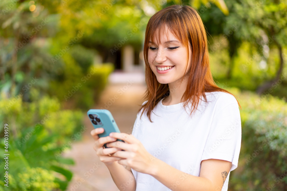 Young pretty redhead woman at outdoors using mobile phone Young pretty redhead woman at outdoors using mobile phone