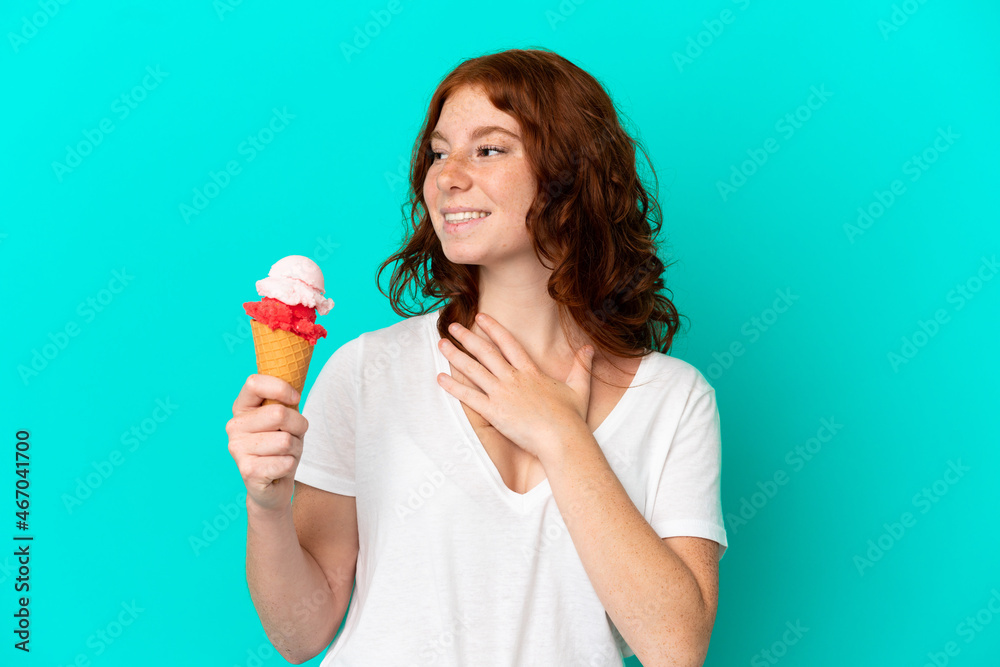 Teenager reddish woman with a cornet ice cream isolated on blue background looking up while smiling Teenager reddish woman with a cornet ice cream isolated on blue background looking up while smiling