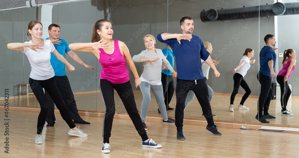 Group of happy adult people enjoying active social dances in modern dance studio