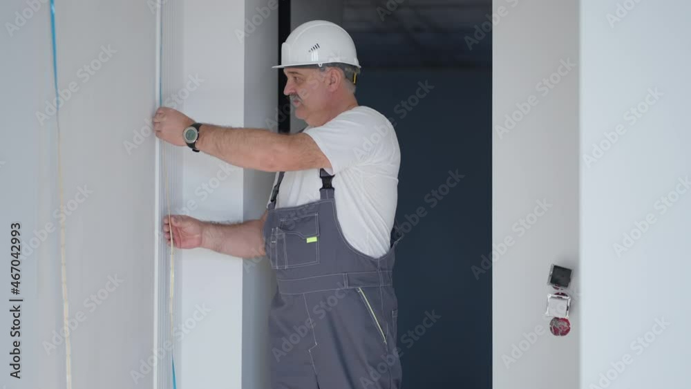 An electrician in a helmet installs and checks LED strips for illumination in the apartment. Check the light and lighting decorative An electrician in a helmet installs and checks LED strips for illumination in the apartment. Check the light and lighting decorative