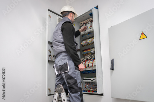 An electrician works in an electrical box. Engineer switches wires in power block