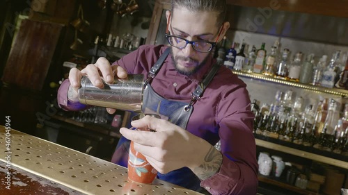 A bartender prepares his drink pouring the mix into the glass photo