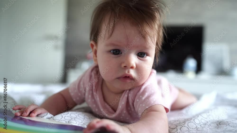 Small caucasian baby four months old lying on the bed at home in bright room in day looking to the side around belly down Small caucasian baby four months old lying on the bed at home in bright room in day looking to the side around belly down
